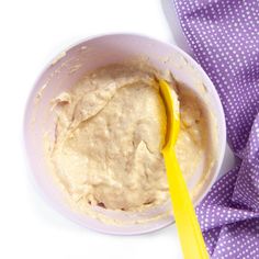 a yellow spoon in a white bowl on a purple and white cloth with polka dots