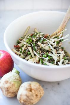 a white bowl filled with food next to an apple