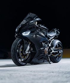 a black motorcycle is parked on the street in front of a dark background with its lights on