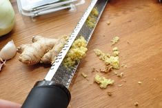 someone is grating up some food on a cutting board next to garlic and ginger