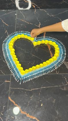 a heart made out of toothpicks sitting on top of a black marble floor