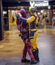 two people in costumes standing next to each other on the floor at an indoor mall