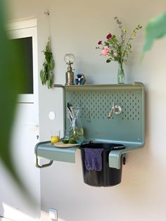 a green sink hanging from the side of a white wall next to a potted plant