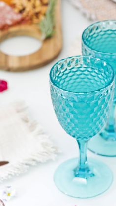 two blue wine glasses sitting on top of a table next to other glassware and napkins