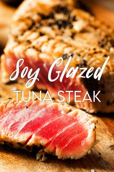 two pieces of tuna on a cutting board with the words soy glazed tuna steak above it