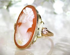 Exquisite vintage cameo ring beautifully crafted of 10K tri-colored gold with a rose gold orange blossom and green colored gold accents on each east/west side of the shell cameo! This elongated oval shaped cameo ring is  bezel set in yellow gold and is so pretty and feminine! It portrays an anonymous woman with what looks to be either wavy shorter hair or in a chignon facing to the right and the workmanship of the cameo details including the floral orange blossom details of this Esemco hallmarke Etsy Engagement Rings Unique, Elongated Oval, Shorter Hair, Unique Engagement Ring, Cameo Ring, Vintage Cameo, Gold Orange, West Side, Unique Engagement