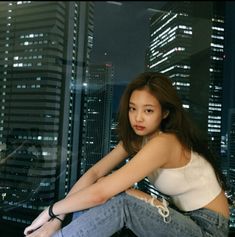 a woman sitting on top of a window sill in front of a cityscape