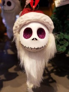 a white skull wearing a santa hat and long white hair with red eyes is hanging from a string