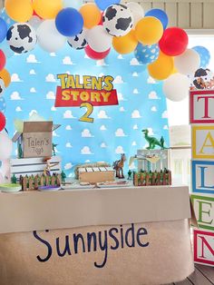 a table topped with lots of balloons next to a sign that reads tales story sunnyside