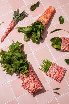 several different types of herbs laid out on a tile floor next to napkins and leaves