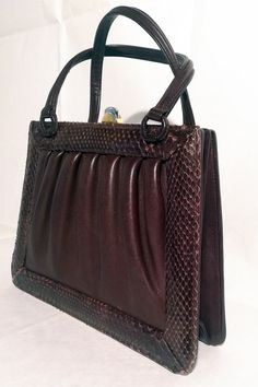 Very charming and full of personality, this rigid handbag, vintage from the 60s. Trapeze shape. Leather and snakeskin print leather, dark brown. Two handles. Gold metal closure with snap button, 2 inside pockets, one with zip. Excellent conditions. Italian craftsmanship. Made in Italy. Measures: Length: 26cm Width: 6cm Height: 20cm Depth: 11cm Handles: 34 cm Vintage Brown Leather Bag, Wedding Bags, Handbag Vintage, Brown Leather Bag, Wedding Bag, Accessories Bags Purses, Vintage Shop, Emilio Pucci, Bags Purses