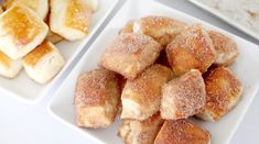 two white plates topped with sugar covered donuts and other pastries next to each other