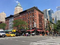 people are walking across the street in front of tall buildings