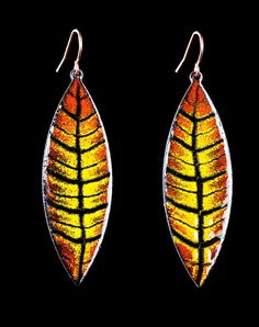 a pair of yellow and orange leaf shaped earrings on black background with clippings