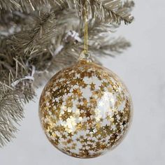 a gold and white ornament hanging from a christmas tree with snow flakes