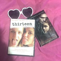 two dvd's and sunglasses laying on top of a pink sheet with the words thirteen