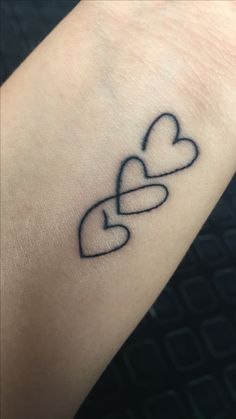 a tattoo with two hearts on the wrist