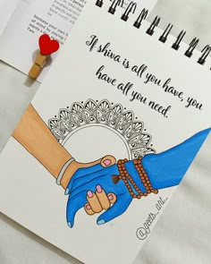 two hands holding each other on top of a notepad next to a pen and pencil