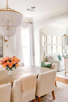 a dining room table with chairs and a chandelier hanging from it's ceiling