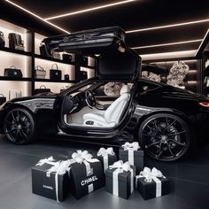 a black sports car with its doors open and some presents in front of it on the floor