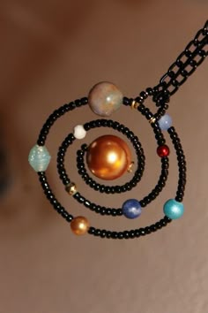 the solar system necklace is made with beads and black string, which are attached to a chain