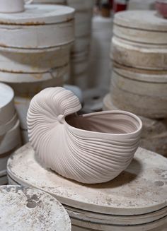 a white bowl sitting on top of a table next to stacks of other plates and bowls