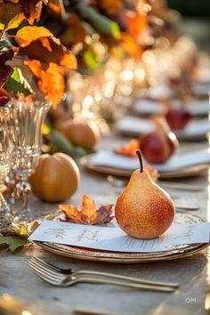 the table is set with plates, silverware and pears in fall leaves on them