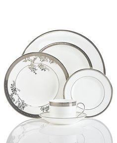 a white and silver dinnerware set with flowers on the rim, is displayed against a white background