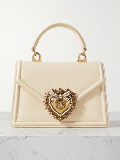 The neat, boxy proportions of Dolce & Gabbana's 'Devotion' bag exude elegance. It's been crafted in Italy from smooth leather with a signature gold-tone heart traced with faux pearls to frame the 'D&G' moniker. It's compact, but there's room for your lipstick, powder and cardholder. Luxury Bags Collection, Flat Dress Shoes, Classic Handbags, Ballet Pumps, Dolce & Gabbana, New Handbags, White Bag, Luxury Items