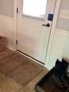 a pair of rubber boots sitting on the floor in front of a door with a basket next to it