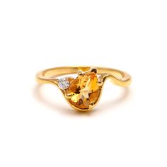 a yellow gold ring with an oval cut citrine and two diamonds on the side