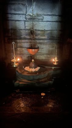 an old fashioned fountain with candles lit in the dark, surrounded by stone walls and flooring