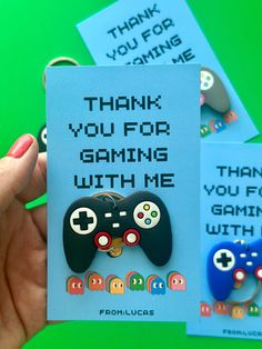 a hand holding a card that says thank you for gaming with me and two video game controllers