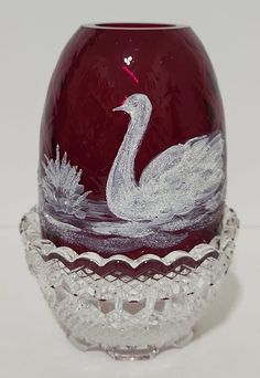 a red glass vase with a white swan on it