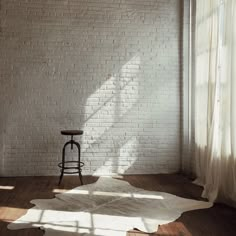 an empty room with white brick walls and wooden floors, there is a chair in the corner