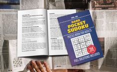 an open book with sudoku on top of it next to other books and papers