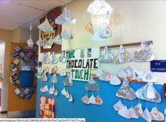 a bulletin board with paper hats hanging from it's sides in a school hallway