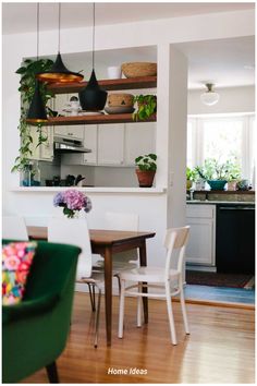 a dining room table and chairs with plants on the shelves above them in a kitchen