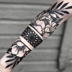 a black and white tattoo with flowers on the arm is shown in this image, it shows