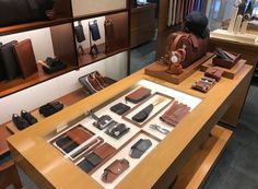 a display case filled with lots of different types of shoes and bags on top of a wooden table