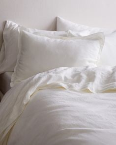 a bed with white sheets and pillows on it