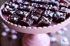 a pink cake plate topped with pieces of chocolate and sprinkled with candy canes