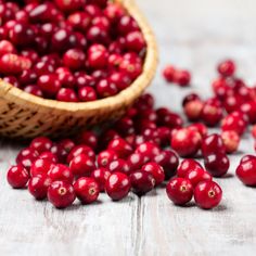 cranberries in a wooden bowl and scattered around on a white wood table top