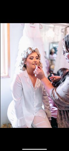 a woman is getting her makeup done by another woman