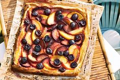 a square pastry with blueberries and peaches on it sitting on a wooden table