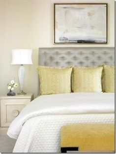 a bedroom with a bed, nightstand and painting on the wall above it's headboard