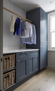 a laundry room with blue cabinets and clothes hanging on a rack above the washer