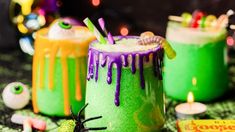 three halloween cocktails with candy and sprinkles on the table next to each other