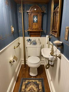 a bathroom with blue walls and wooden floors, including a toilet in the corner next to a sink