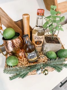 an arrangement of alcohol, limes and ginger ale in a basket on a table